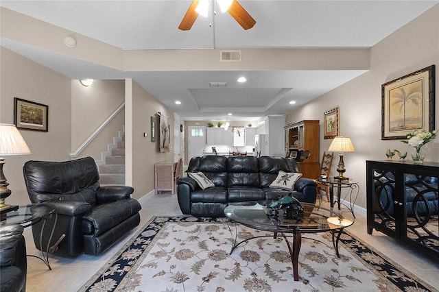 living room featuring light tile patterned flooring, ceiling fan, and a raised ceiling