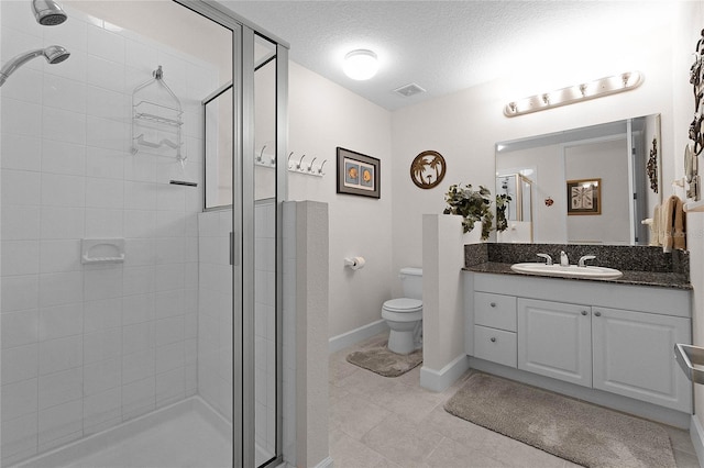 bathroom featuring vanity, toilet, a textured ceiling, and a shower with shower door