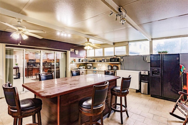 kitchen with white cabinetry, black fridge, light tile patterned floors, and ceiling fan