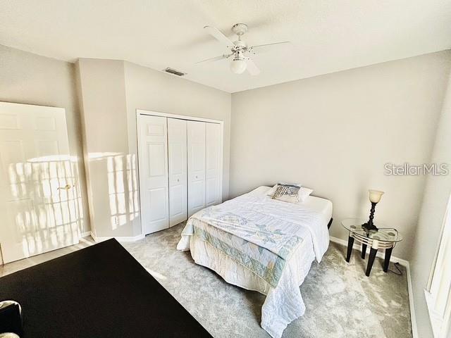 carpeted bedroom featuring a closet and ceiling fan