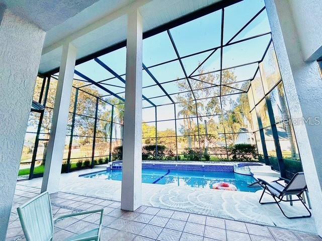 view of swimming pool featuring a lanai, a patio area, and an in ground hot tub