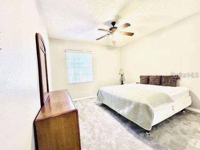 carpeted bedroom with a textured ceiling and ceiling fan