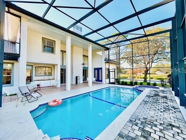 view of pool with an in ground hot tub, ceiling fan, a patio, and glass enclosure