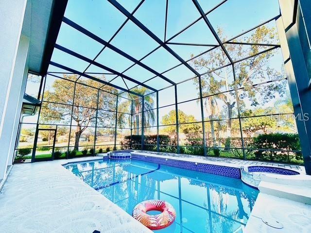 view of pool featuring an in ground hot tub, a patio, and glass enclosure