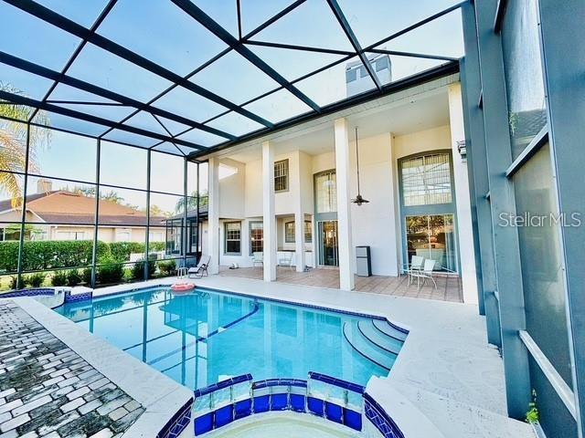 view of pool featuring an in ground hot tub, a patio, and glass enclosure