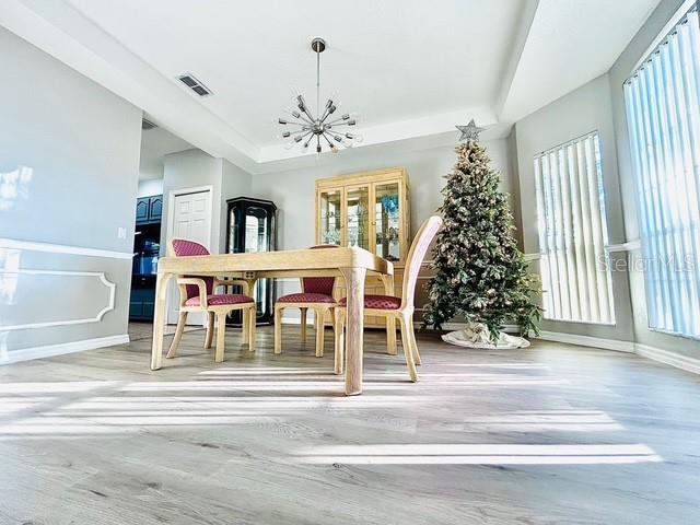 dining area with a chandelier, a raised ceiling, visible vents, and a healthy amount of sunlight