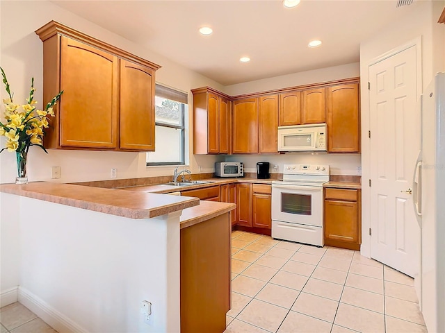 kitchen with sink, light tile patterned floors, white appliances, and kitchen peninsula