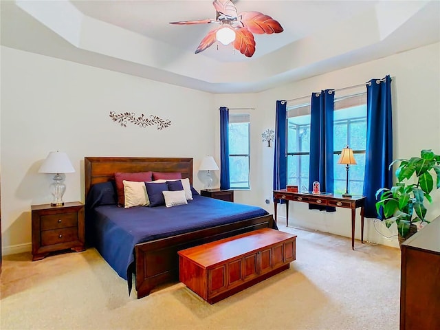 bedroom with light carpet, a raised ceiling, and ceiling fan