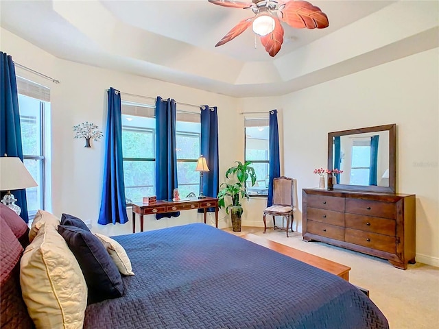 bedroom featuring ceiling fan, a raised ceiling, and multiple windows