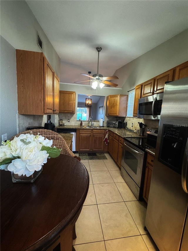 kitchen featuring sink, vaulted ceiling, light tile patterned floors, kitchen peninsula, and stainless steel appliances