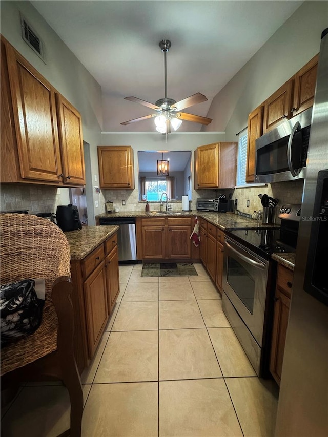 kitchen with lofted ceiling, light tile patterned floors, decorative backsplash, and stainless steel appliances