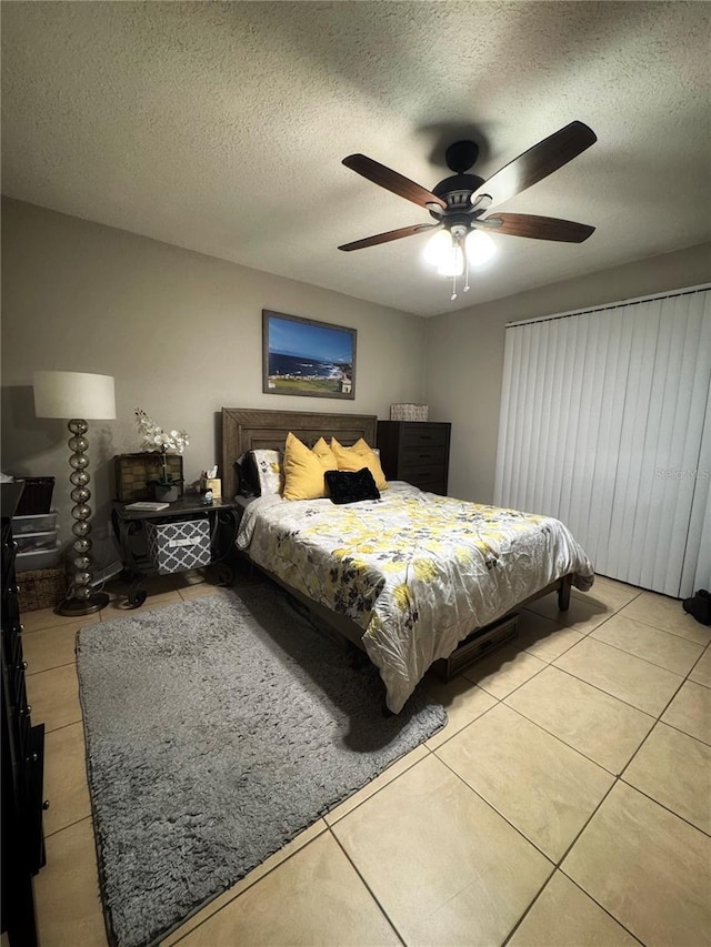 tiled bedroom with a textured ceiling and ceiling fan