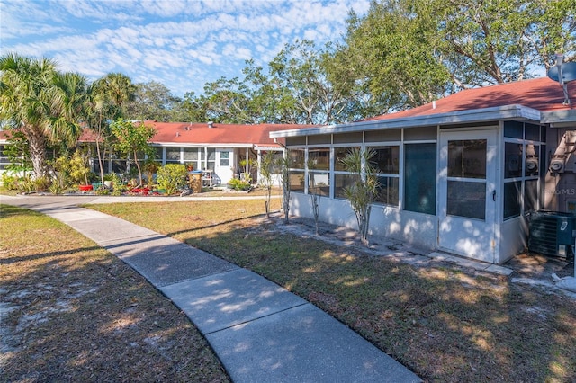 view of front of property with cooling unit, a front lawn, and a sunroom