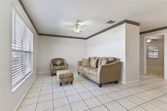 tiled living room with ceiling fan, ornamental molding, and a textured ceiling