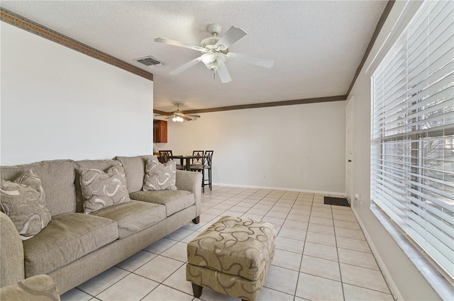 tiled living room with ornamental molding, ceiling fan, and a textured ceiling