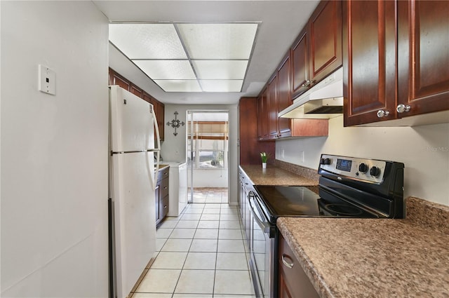 kitchen with light tile patterned floors, range with electric cooktop, and white fridge