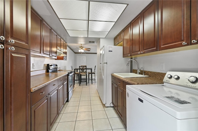 kitchen featuring light tile patterned floors, sink, ceiling fan, stainless steel electric range oven, and washer / dryer