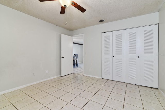 unfurnished bedroom featuring light tile patterned flooring, ceiling fan, a closet, and a textured ceiling