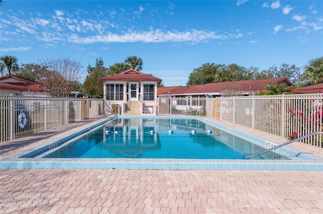 community pool with an outdoor structure, a storage structure, and fence
