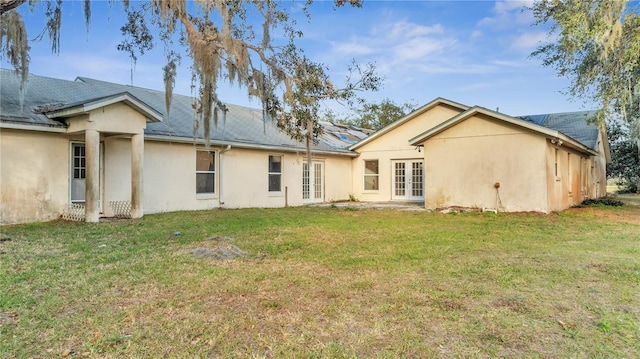 back of property featuring french doors and a lawn