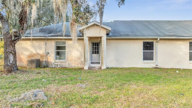 rear view of property with cooling unit and a yard