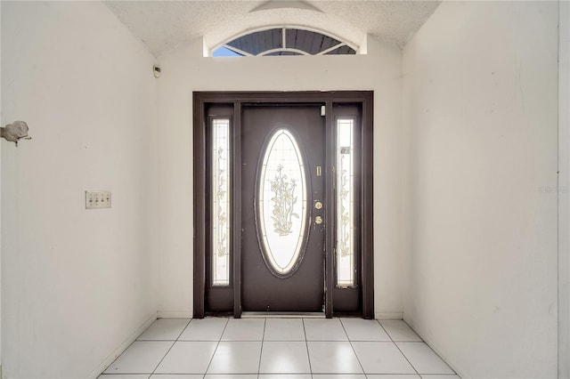 tiled foyer entrance with lofted ceiling and a textured ceiling