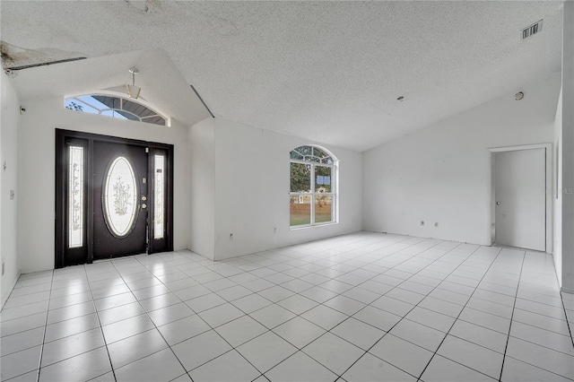 entryway featuring light tile patterned floors, vaulted ceiling, and a textured ceiling