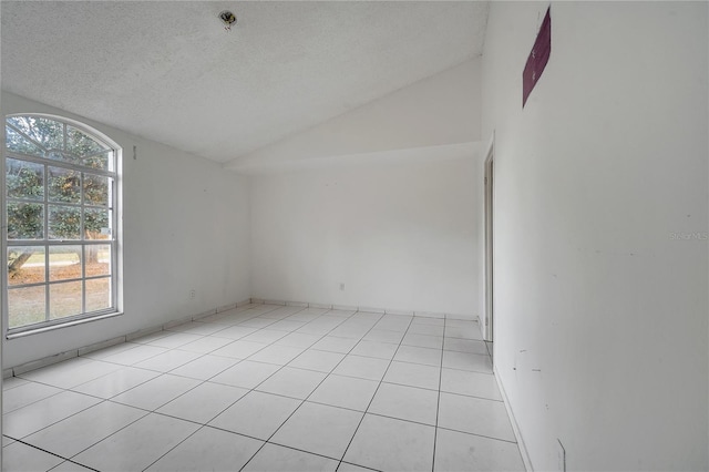 spare room with light tile patterned flooring, vaulted ceiling, and a textured ceiling