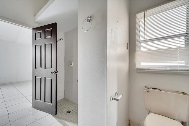 bathroom featuring toilet, tile patterned flooring, and a tile shower