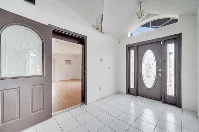 tiled entryway featuring lofted ceiling and a textured ceiling