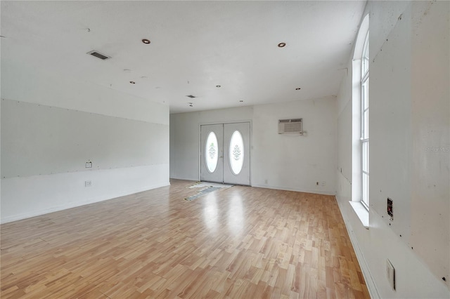 entrance foyer featuring a wall mounted air conditioner, light hardwood / wood-style flooring, and french doors