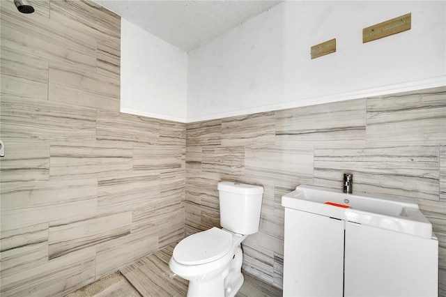 bathroom with vanity, tile walls, a textured ceiling, and toilet