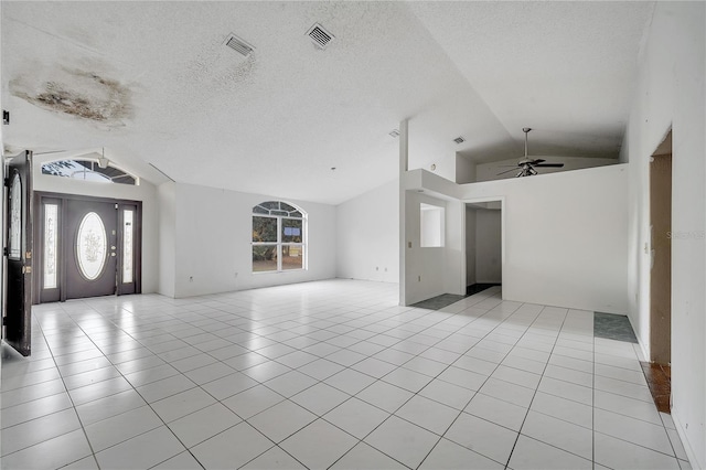 unfurnished living room with ceiling fan, vaulted ceiling, a textured ceiling, and light tile patterned floors