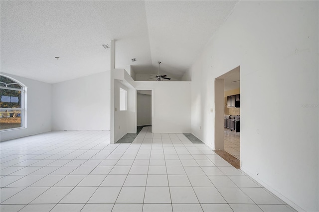 tiled spare room with a textured ceiling, vaulted ceiling, and ceiling fan