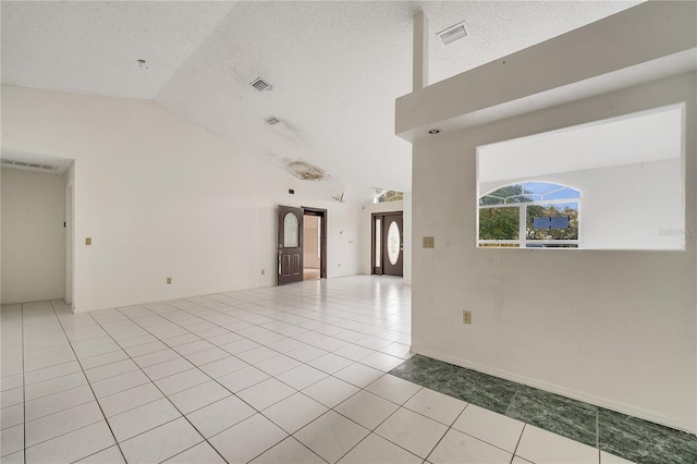 empty room with lofted ceiling, light tile patterned floors, and a textured ceiling