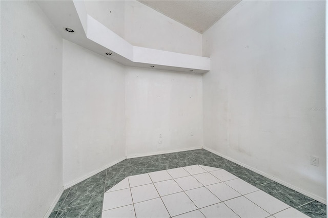 spare room with high vaulted ceiling and tile patterned flooring