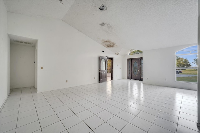 empty room featuring light tile patterned flooring, lofted ceiling, and a textured ceiling