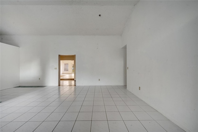 empty room with lofted ceiling and light tile patterned floors