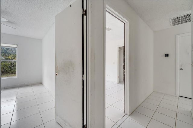 hall featuring light tile patterned flooring and a textured ceiling