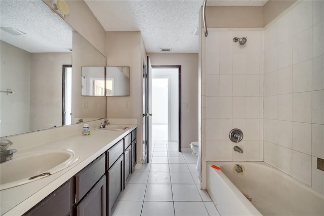 full bathroom with toilet, a textured ceiling, vanity, tiled shower / bath combo, and tile patterned flooring