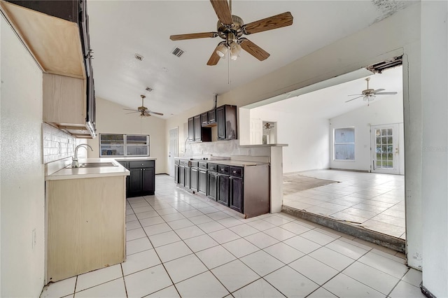 kitchen with sink, dark brown cabinets, vaulted ceiling, and light tile patterned flooring