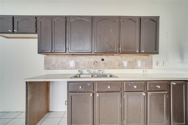 kitchen with dark brown cabinets, sink, and light tile patterned floors