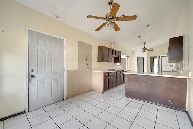 kitchen featuring lofted ceiling, sink, light tile patterned floors, and dark brown cabinetry