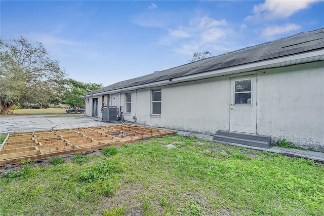 back of property with a patio area, a lawn, and central air condition unit