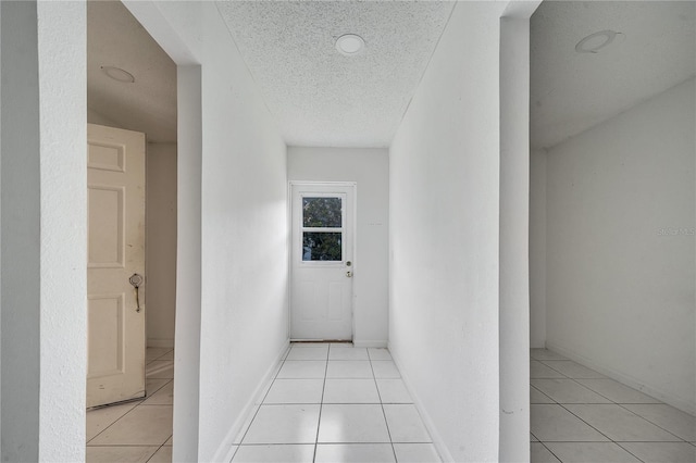 hall featuring light tile patterned floors and a textured ceiling