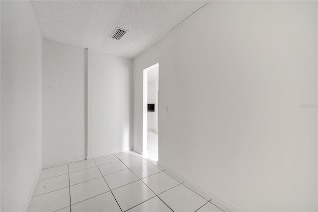 empty room with a textured ceiling and light tile patterned flooring