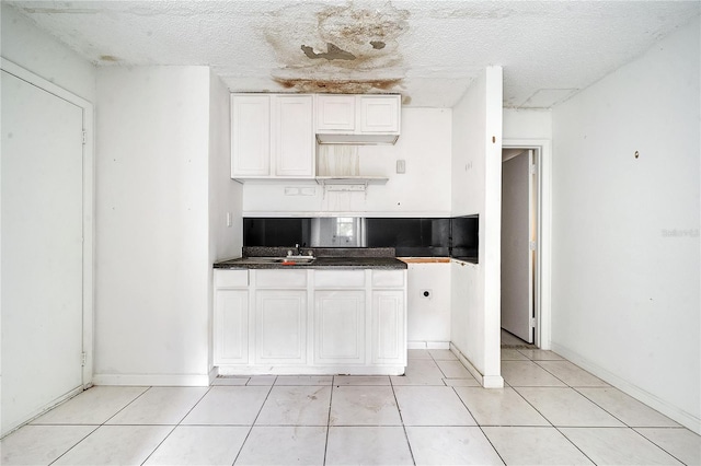 kitchen with white cabinetry, sink, a textured ceiling, and light tile patterned floors