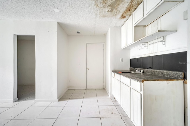 kitchen featuring white cabinetry, sink, a textured ceiling, and light tile patterned floors