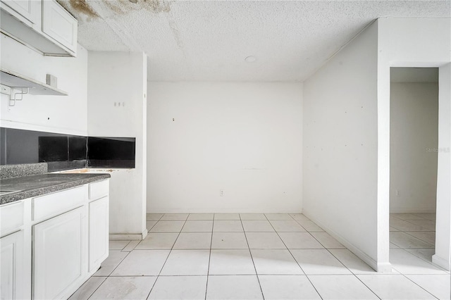 kitchen featuring white cabinetry, a textured ceiling, and light tile patterned floors