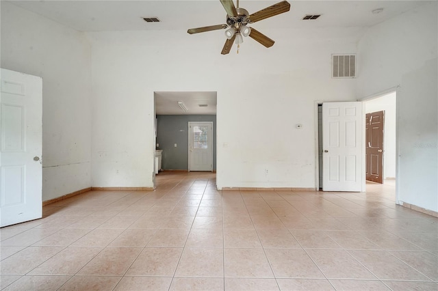 tiled spare room featuring ceiling fan and a high ceiling